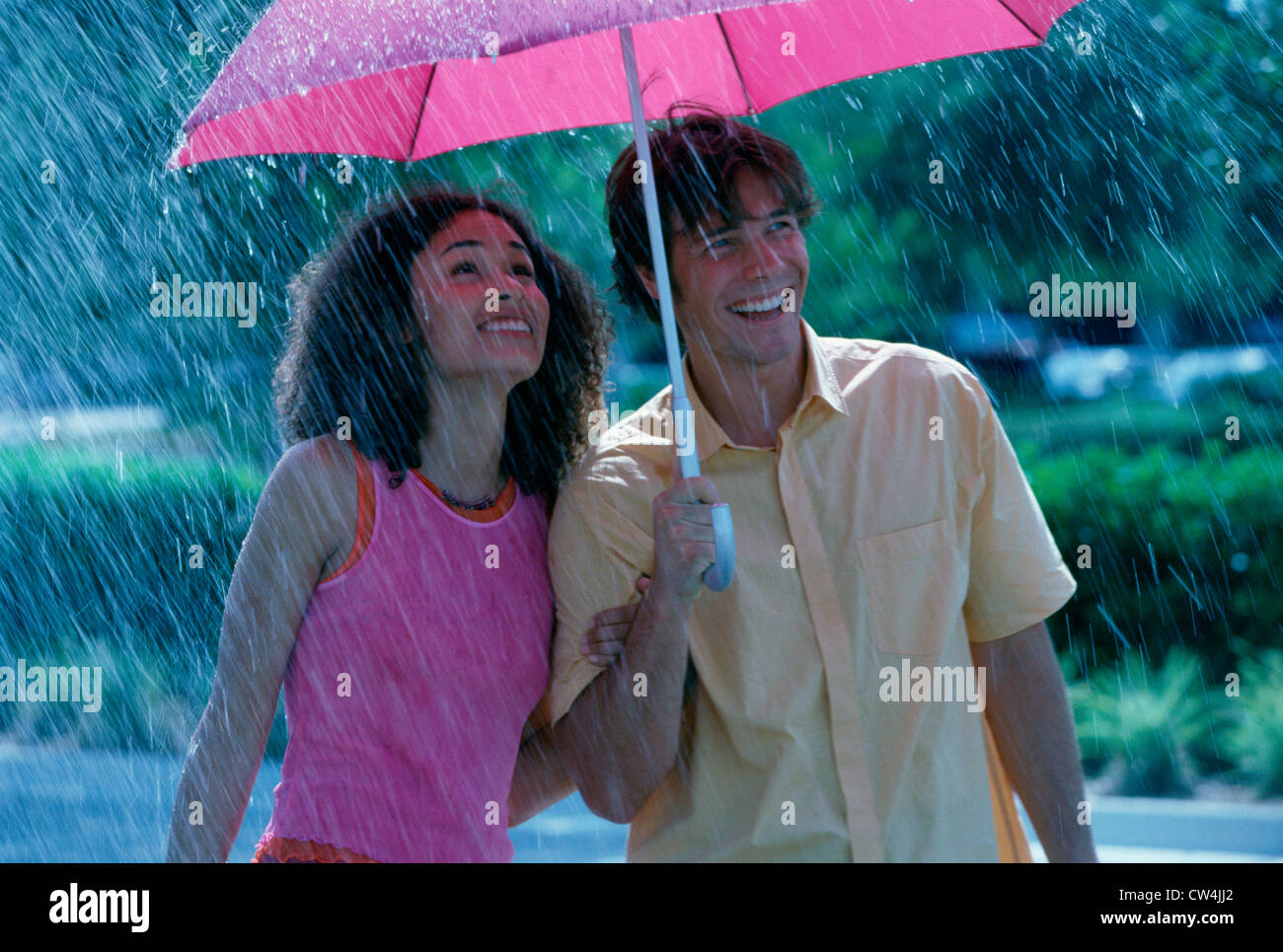 Young couple standing in the rain with an umbrella Stock Photo - Alamy
