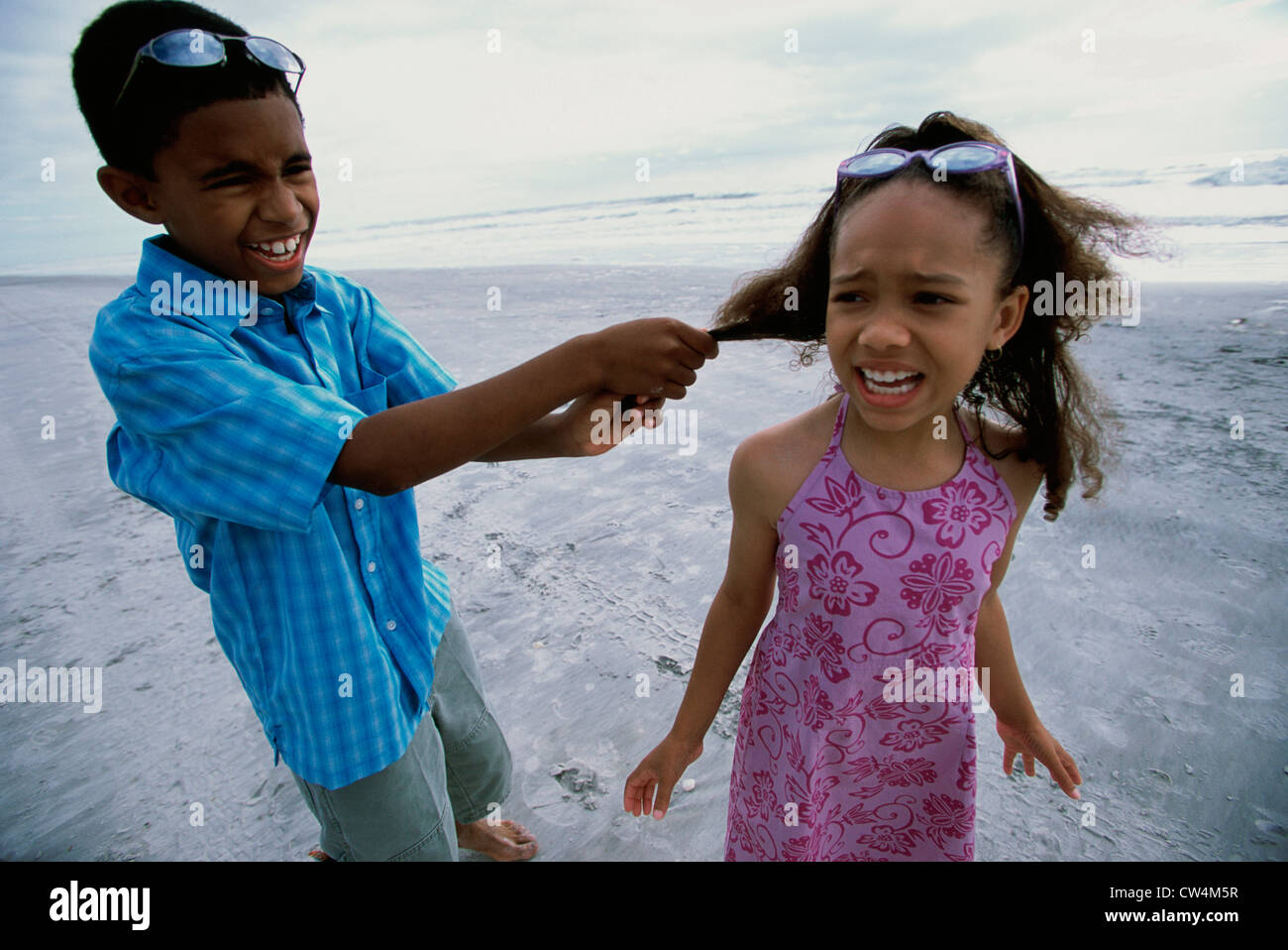 Boy pulling a girl's hair on the beach Stock Photo - Alamy