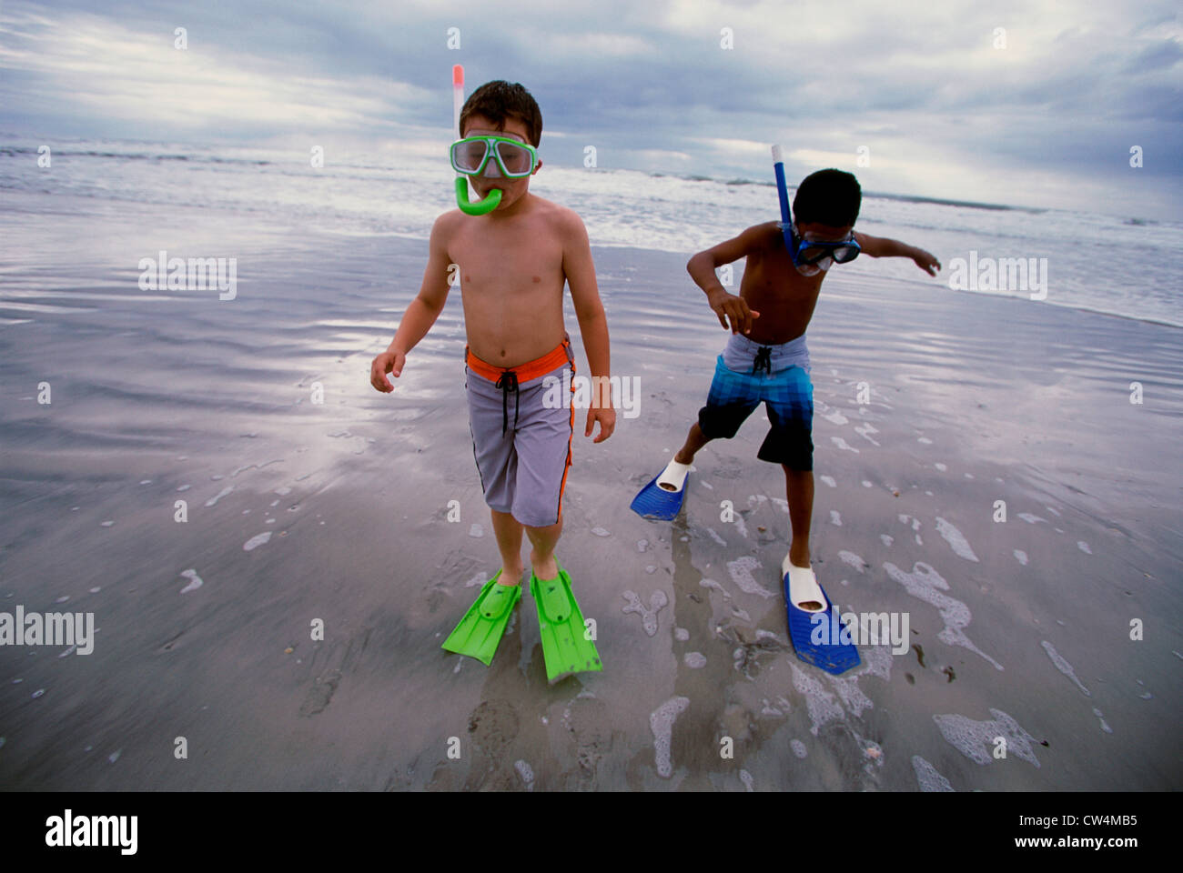 Two boys wearing snorkels and flippers walking on the beach Stock Photo