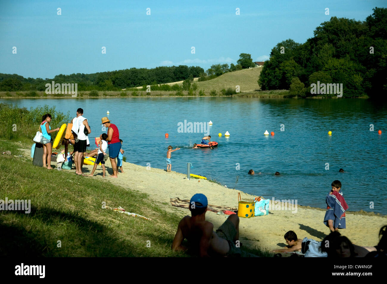 Summer visitors enjoy an inland bathing lake and its 'imported' sand beach in Lupiac, southwest France Stock Photo