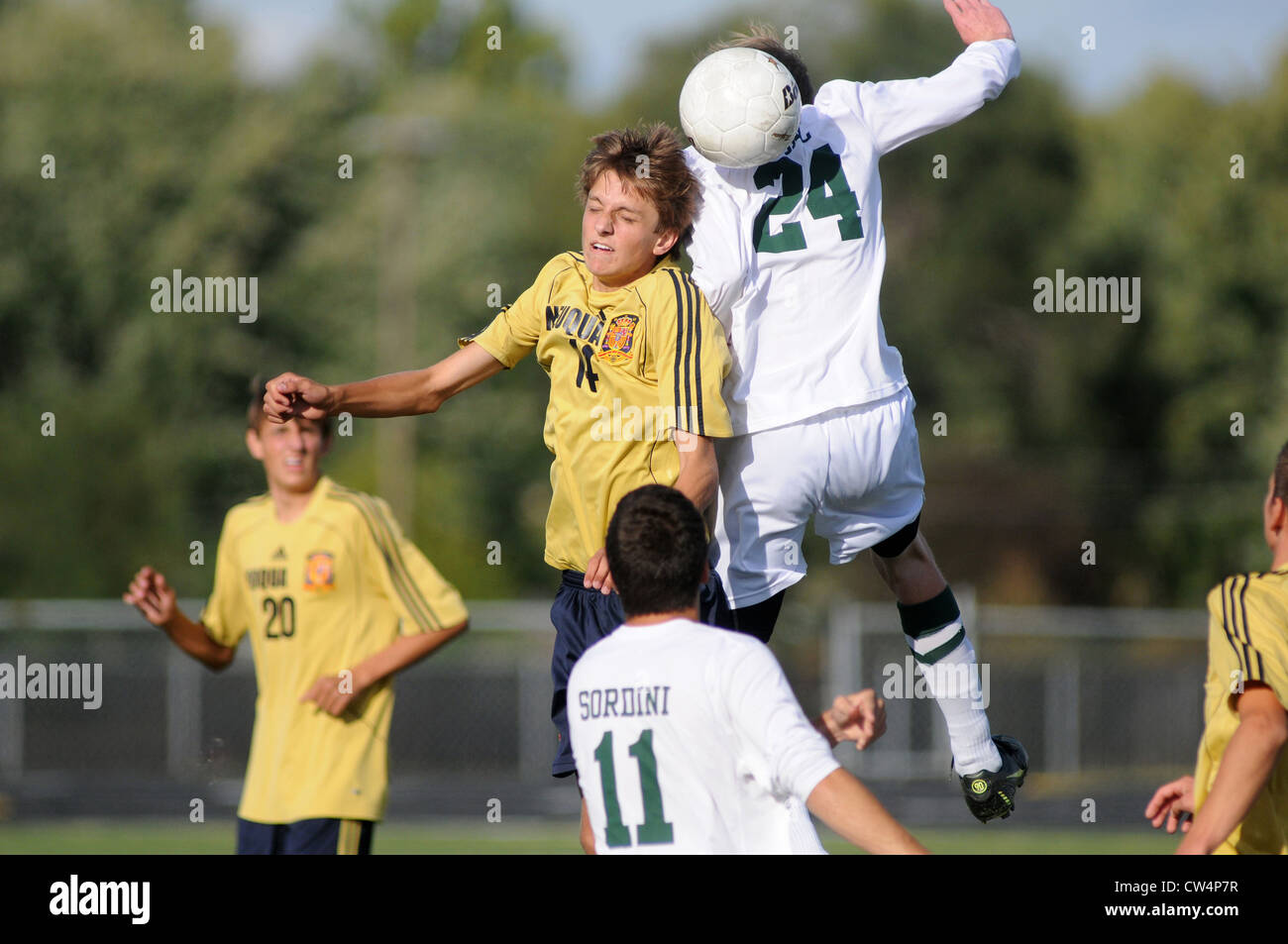 Soccer Players use a header to redirect the flight of the ball during a high school match. Stock Photo