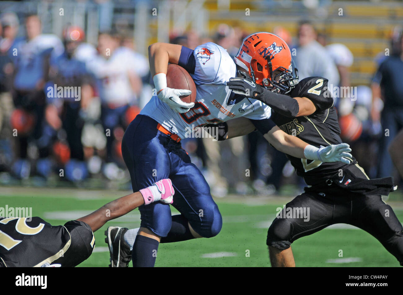 Football running back brought down by a pair of tacklers. USA. Stock Photo