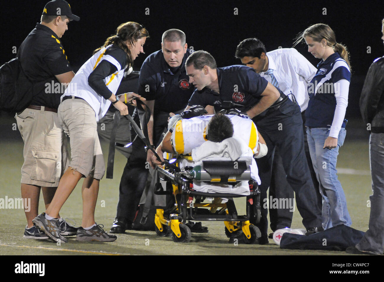 Football Player with broken leg is removed from field on stretcher after initial treatment by medical staff during a game. USA. Stock Photo