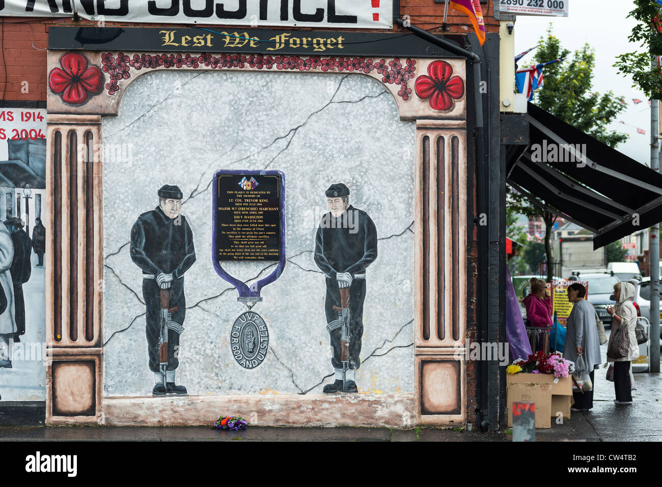 Local people at grocers with Political mural on Shankill road, Belfast in Northern Ireland. Stock Photo