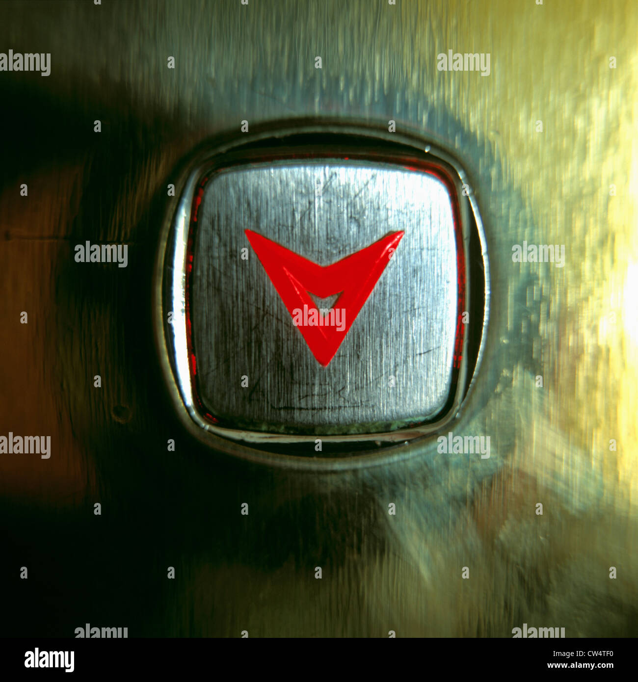 Close-up of an elevator button with a glowing red arrow pointing down Stock Photo