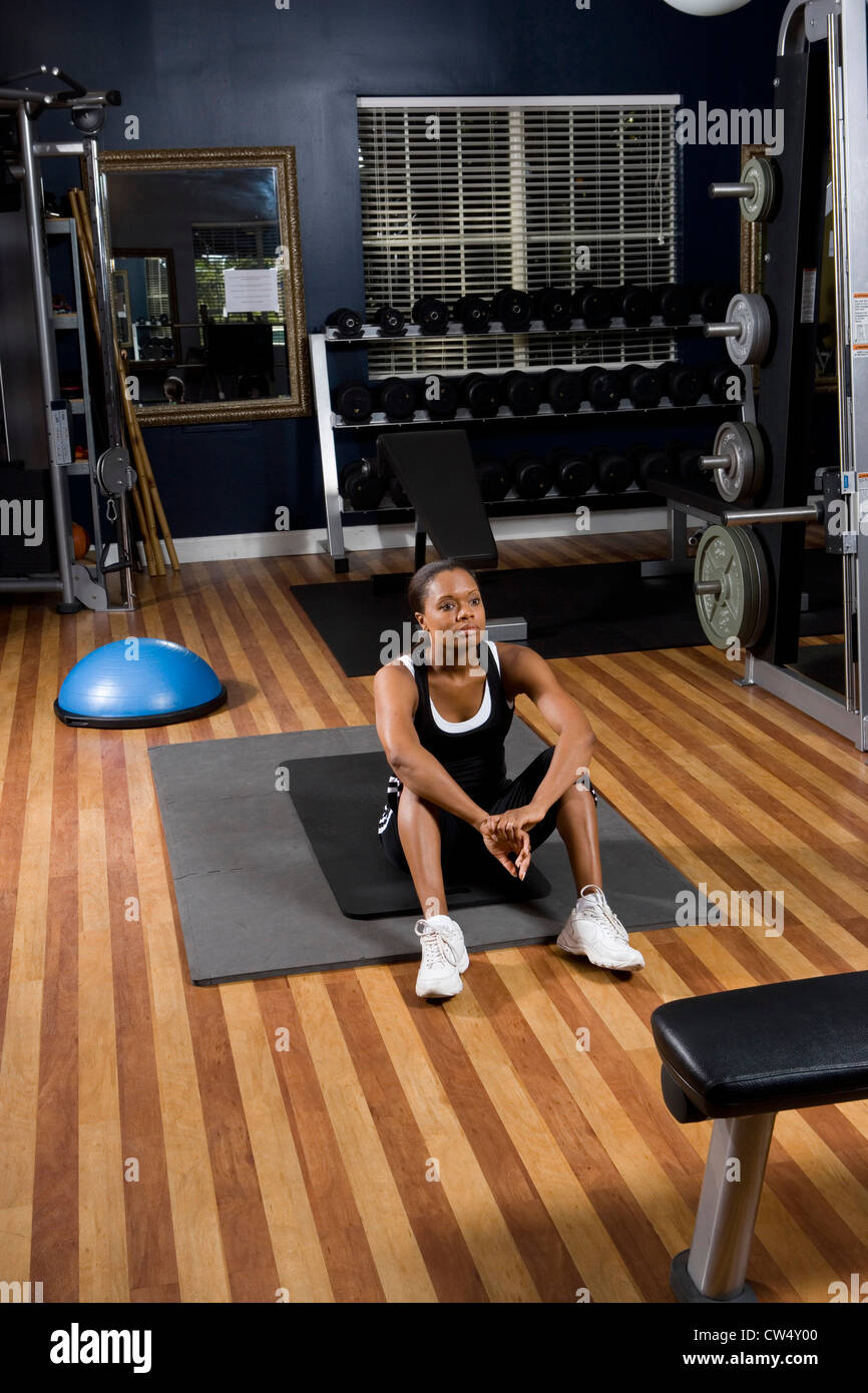 Contemplative young woman sitting on a mat in the gym Stock Photo - Alamy