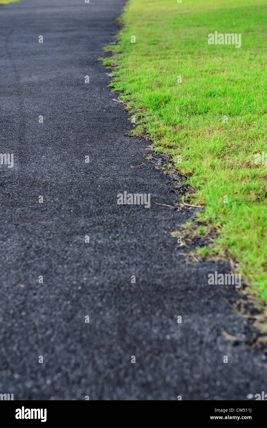 Close up asphalt road is along with grass,abstract between synthesis and nature Stock Photo