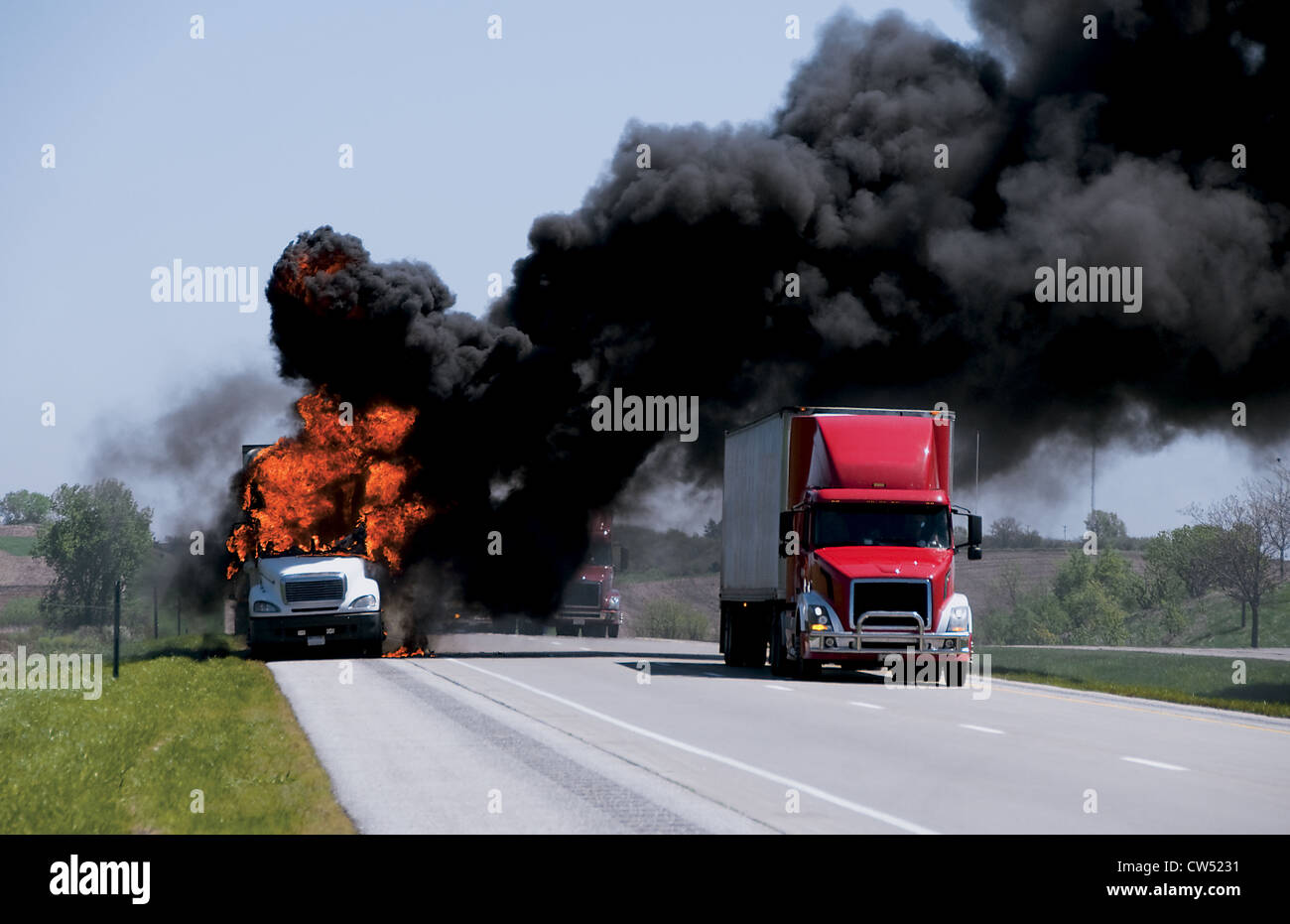 Tractor-trailers passing burning truck on shoulder of Interstate 80 near Marengo, Iowa Stock Photo