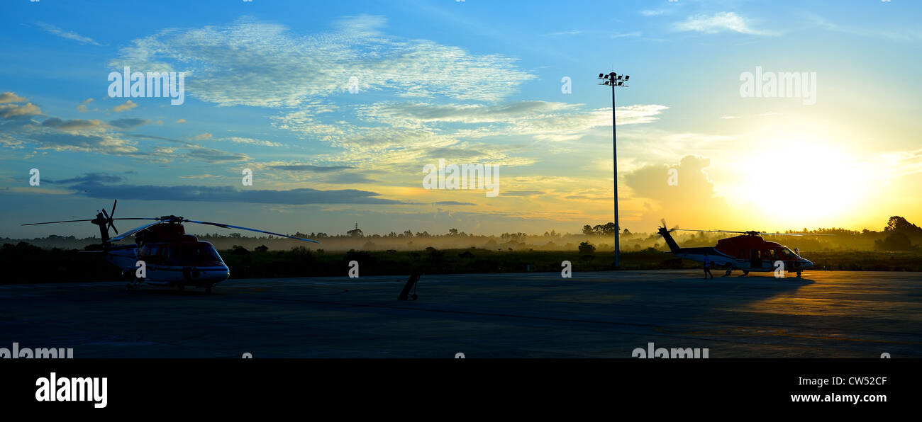 silhouette of helicopters on the apron with sunrise background Stock Photo
