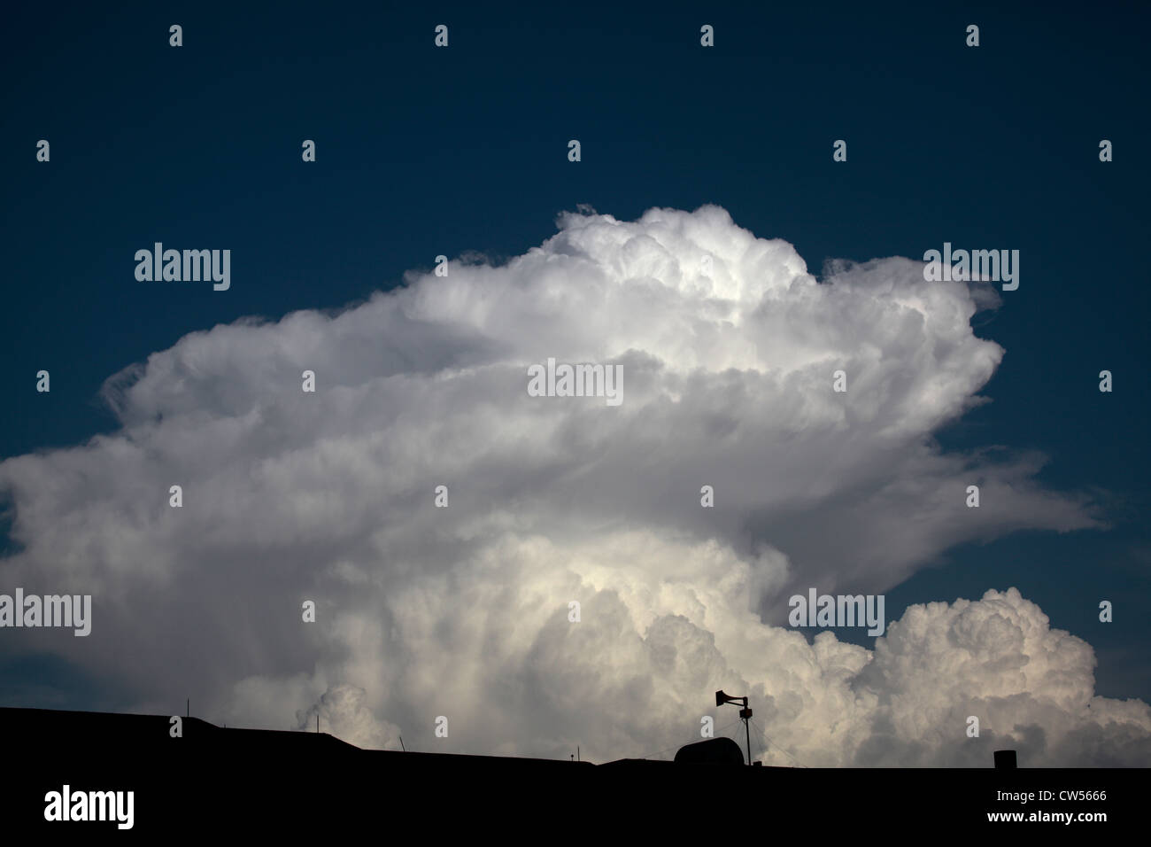 Rotating area of convection near top of rapidly forming cumulus cloud, with alert siren in lower corner. Stock Photo