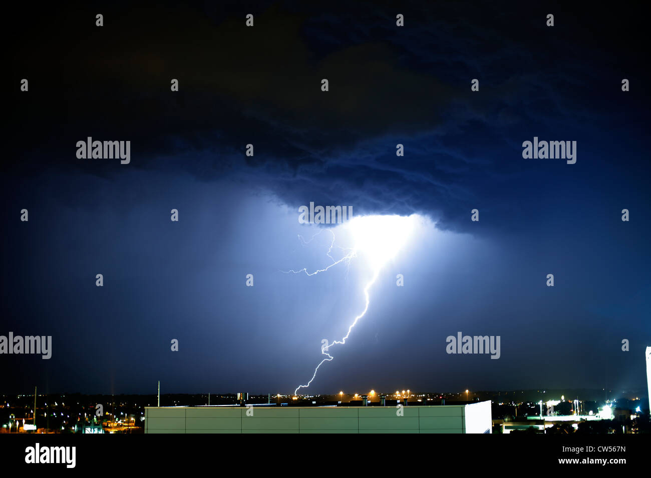 Lightning strike and city lights at night. Stock Photo