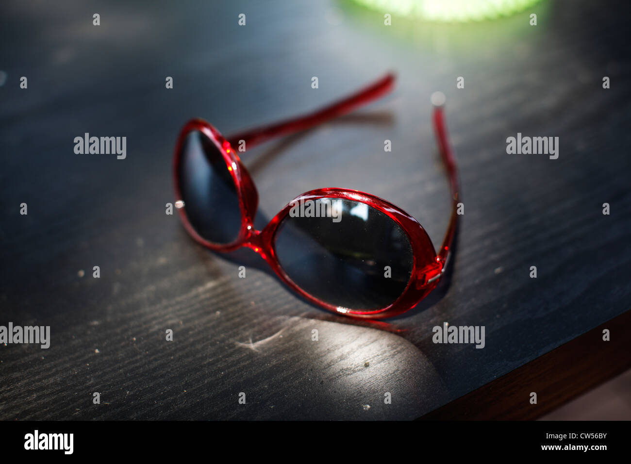 Red plastic women's sunglasses on black surface. Stock Photo