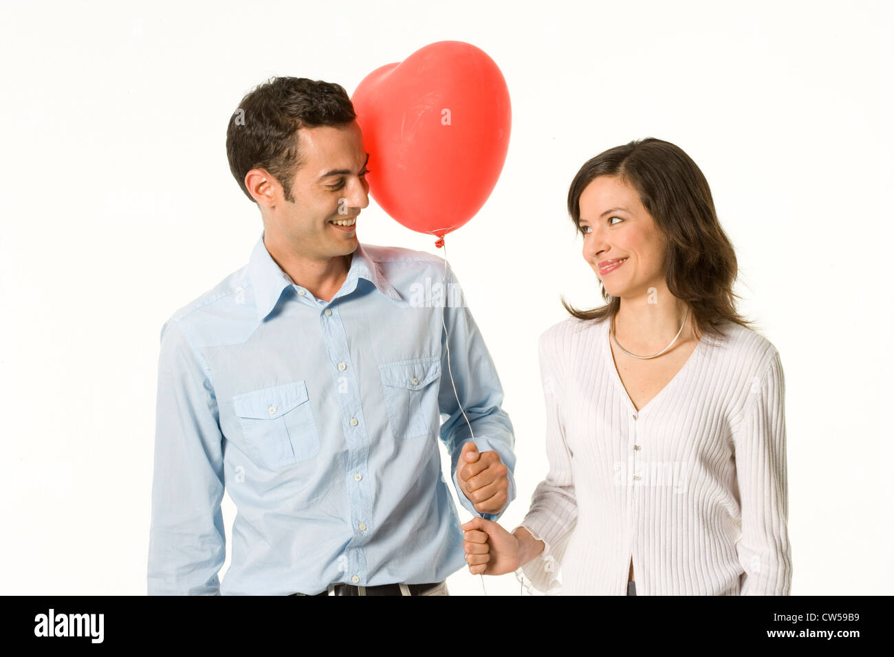 Young couple holding a heart shape balloon and looking at each other ...
