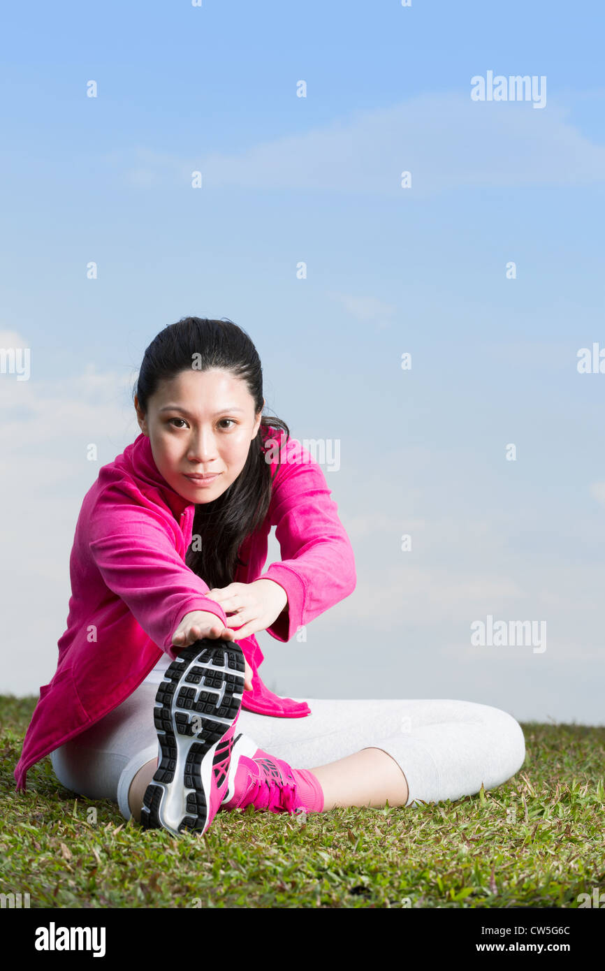 Chinese woman doing sit ups in park. Stock Photo