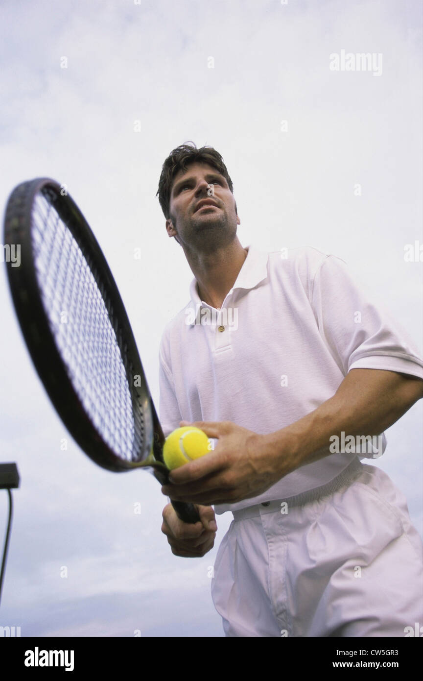 Low angle view of man holding a tennis ball and a tennis racket Stock Photo