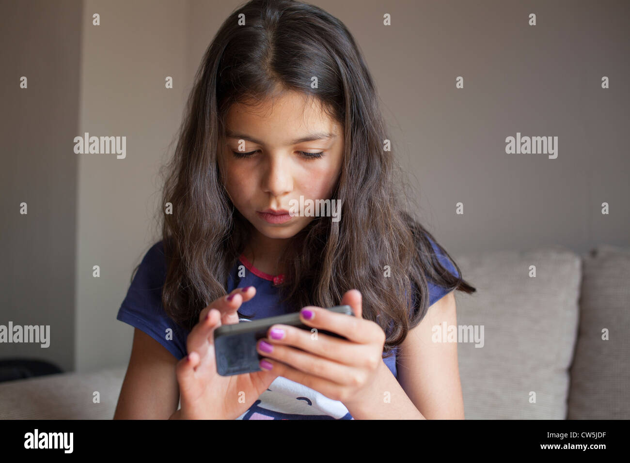 Young girl plays on mobile phone at home Stock Photo