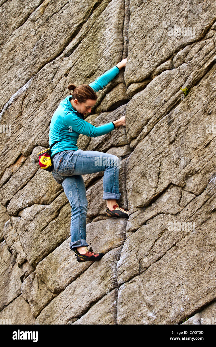 A young women rock climbs a crack at Burbage, Sheffield, near Stanage in the Peak District National Park, England, UK, Europe Stock Photo