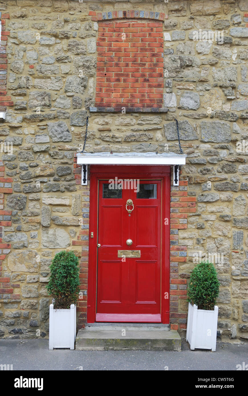 Red painted wooden door in brick and stone wall of house in Petworth ...