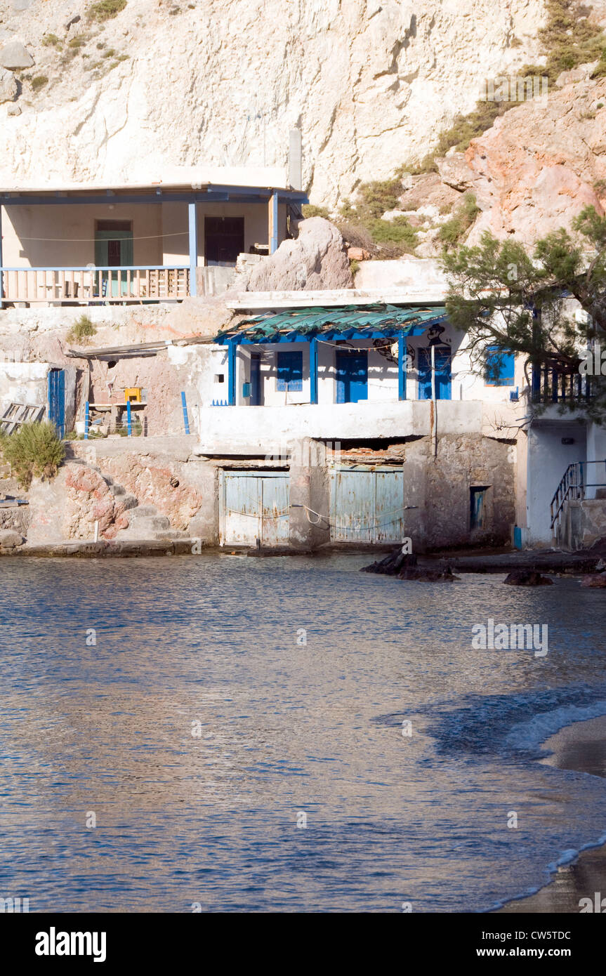 fisherman houses built into rock cliffs on Mediterranean Sea Firopotamos Milos Cyclades Greek Island Greece Stock Photo