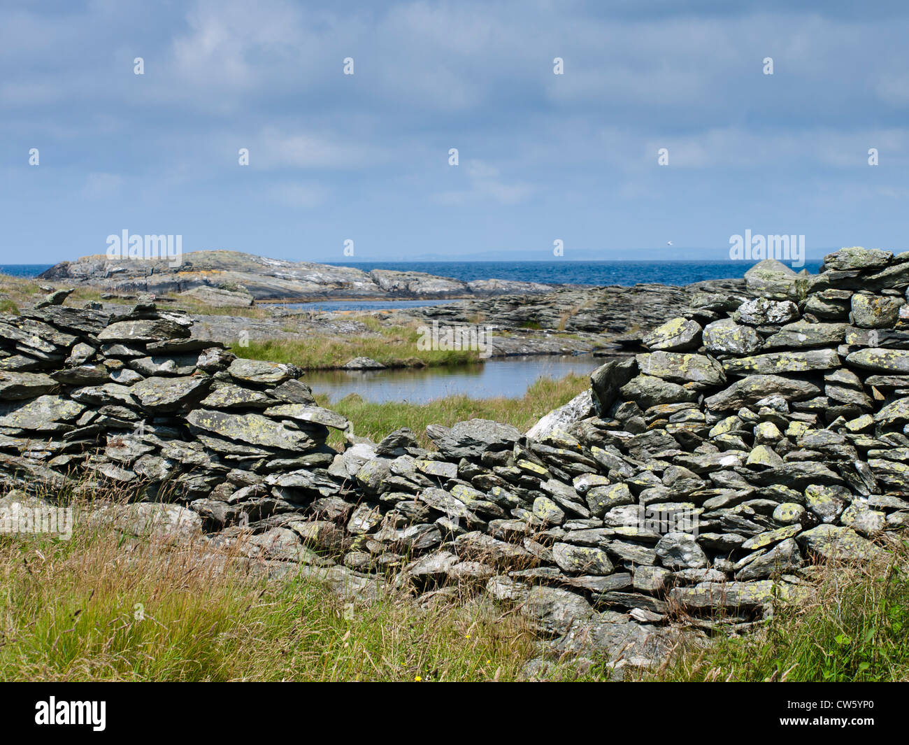 Stone fence wall with an opening framing rocks, shoreline and the north sea near Stavanger Norway Stock Photo