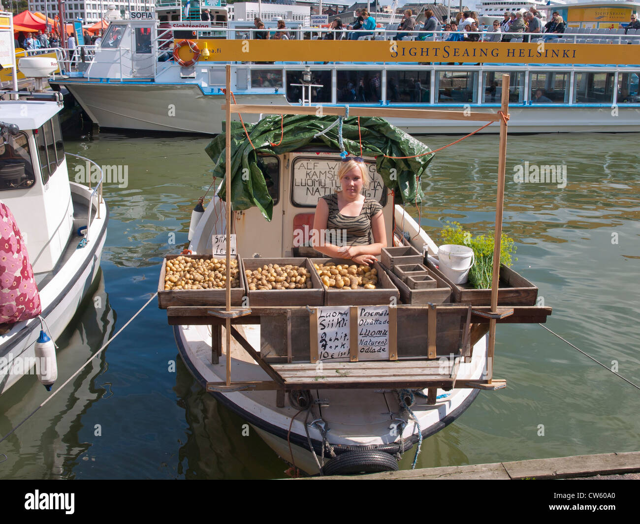Woman selling potatoes and dill from her boat in the farmer´s marked i central Helsinki Stock Photo