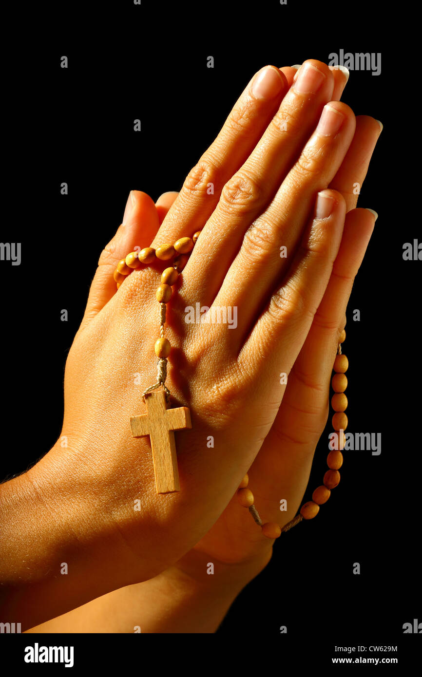 Christian human praying with rosary in hands Stock Photo