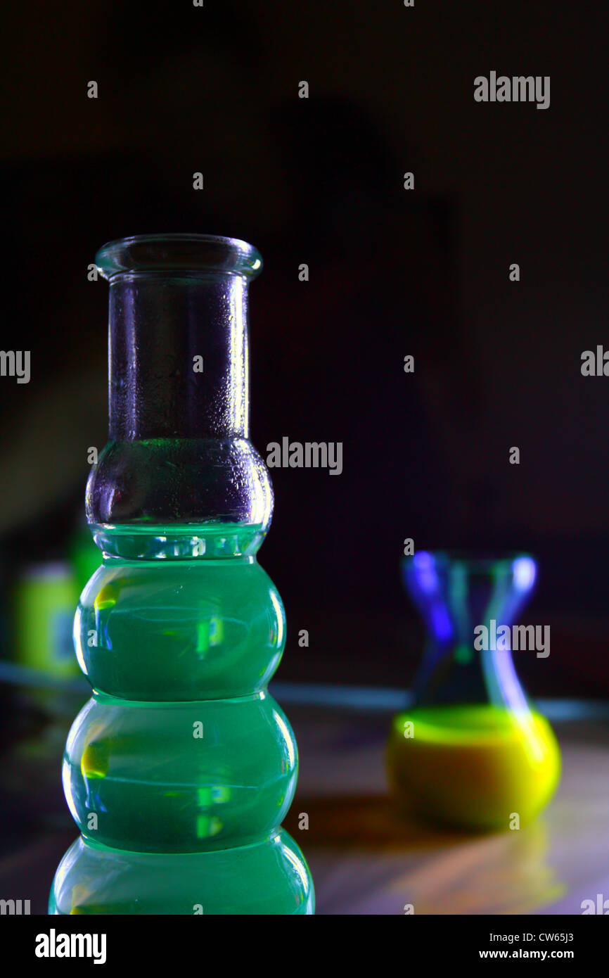 Two vases filled with fluorescent drinks viewed under UV light, with lens effect Stock Photo