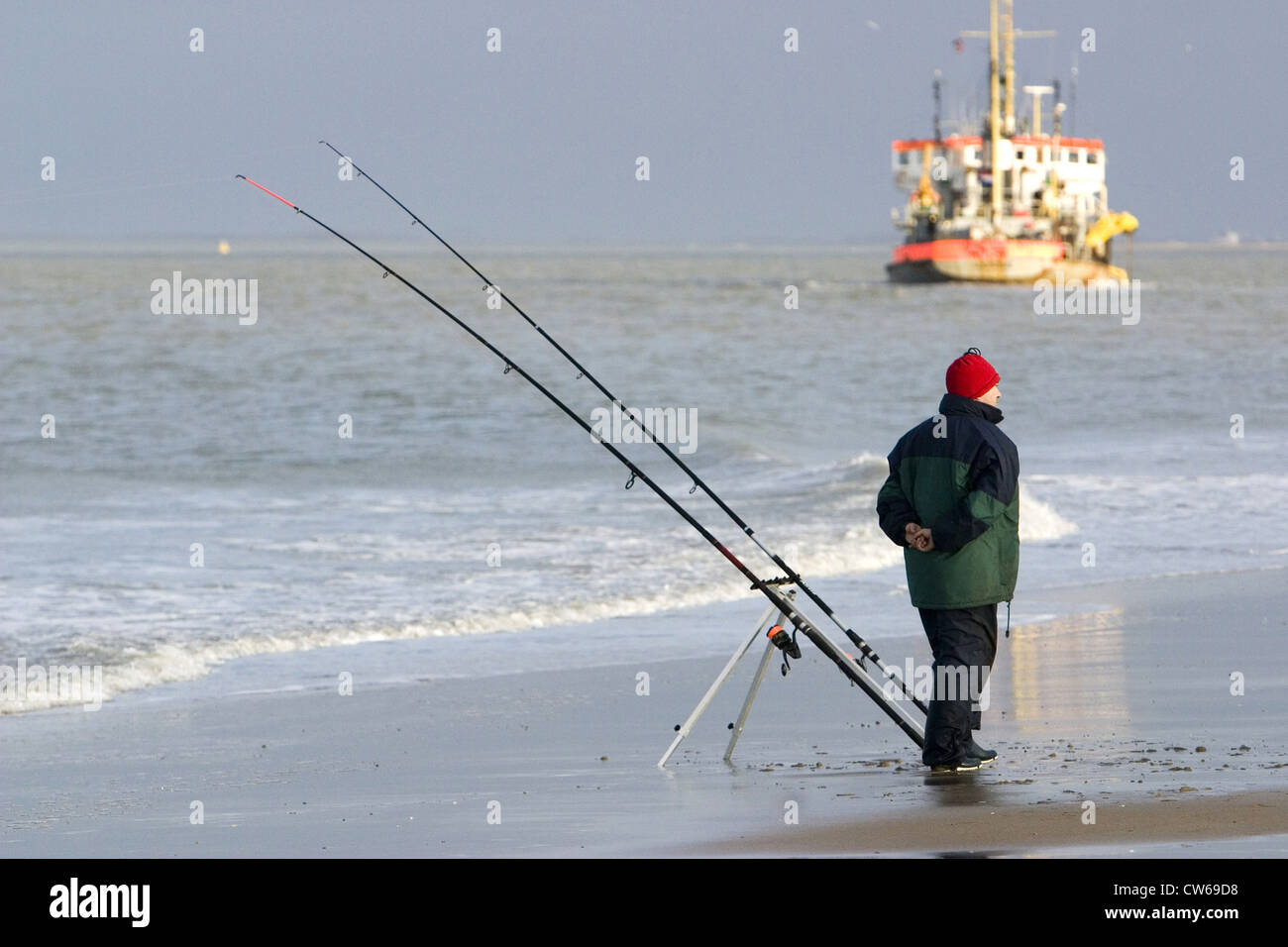 angler at the beach, ship in background, Netherlands, Zeeland, Breskens Stock Photo