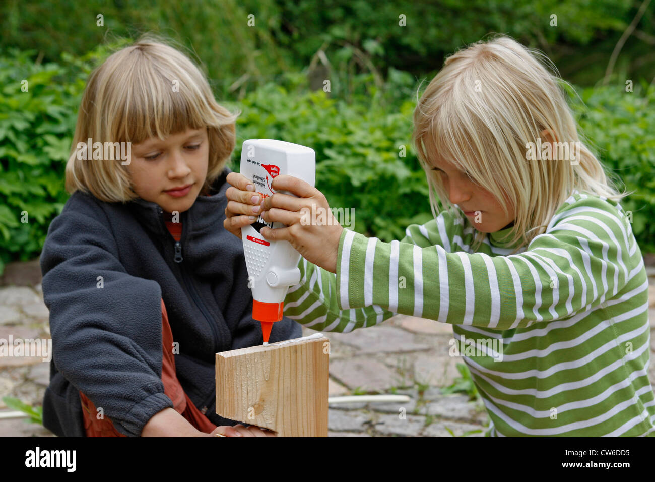 children tinkering an apple dryer, putting on wood glue, Germany Stock Photo