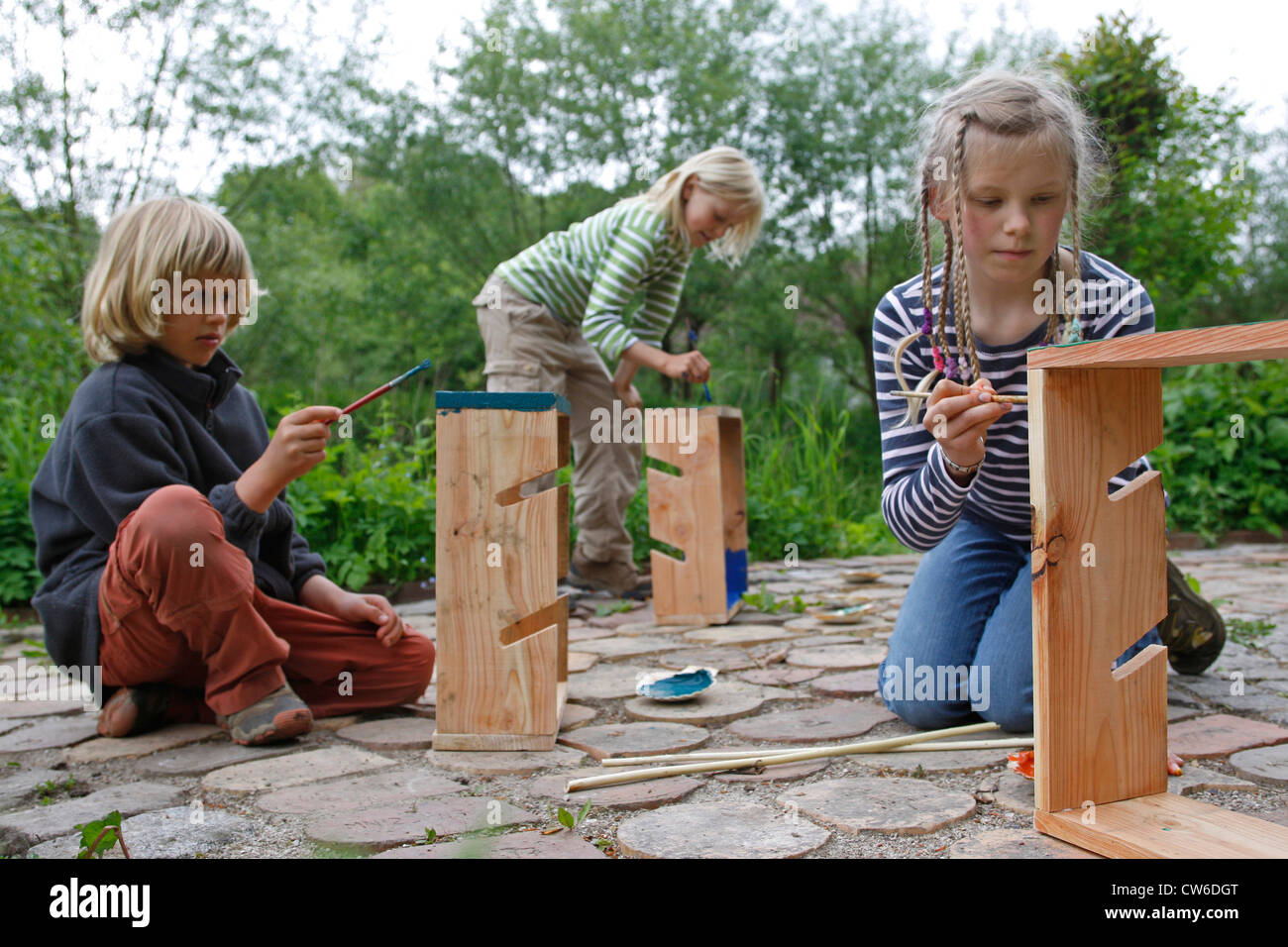 children are making an apple dehydrator; children are painting their finished apple dehydrators in bright colors, Germany Stock Photo