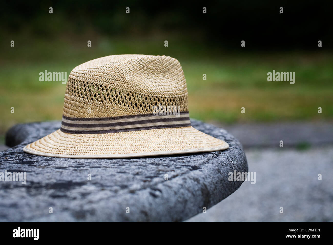 Man's straw hat on an old stone bench. Stock Photo