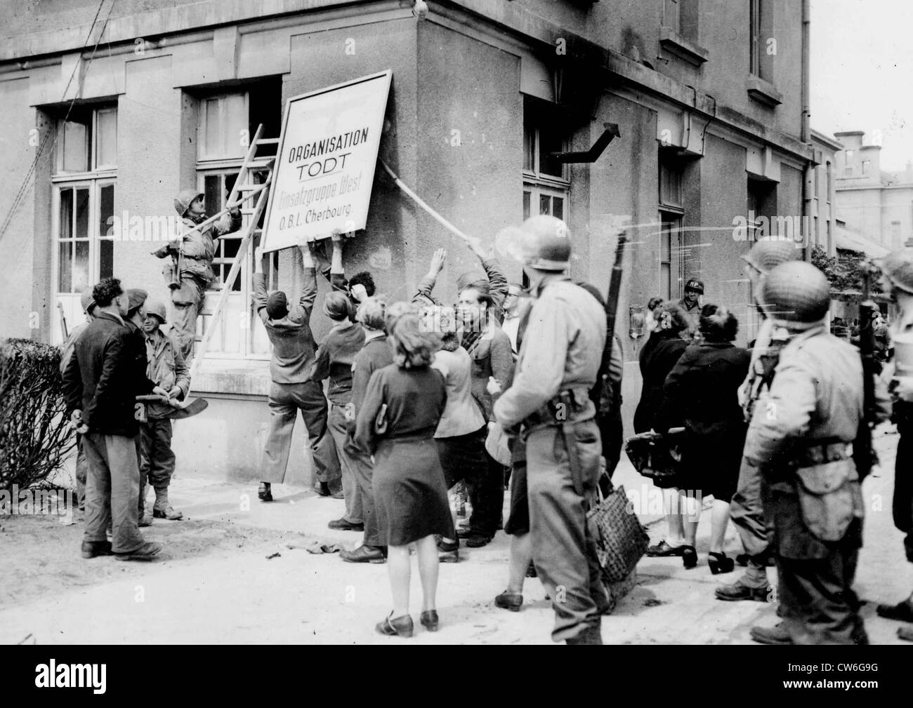 The population of Cherbourg putting down the insignia of the Todt Organisation just after the town's liberation Stock Photo