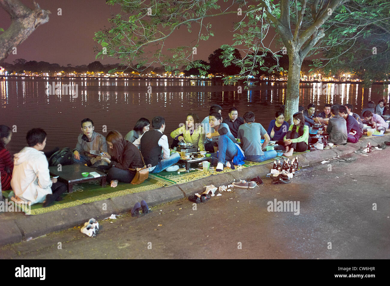 People sitting by the side of the road eating at restaurants by the West Lake in Vietnam. Stock Photo