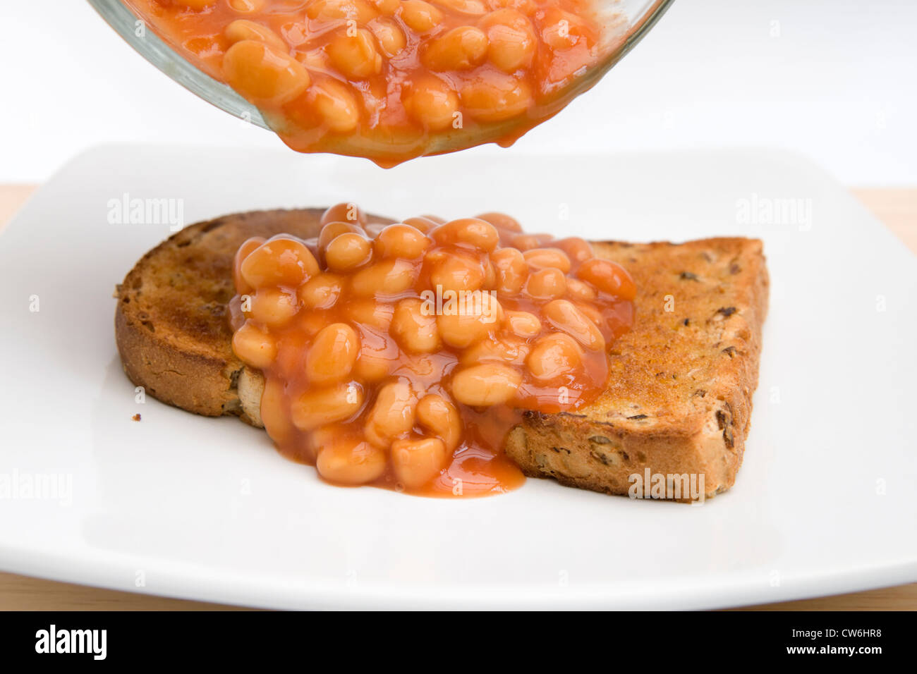Pouring baked beans onto slice of granary bread on white plate Stock Photo Alamy