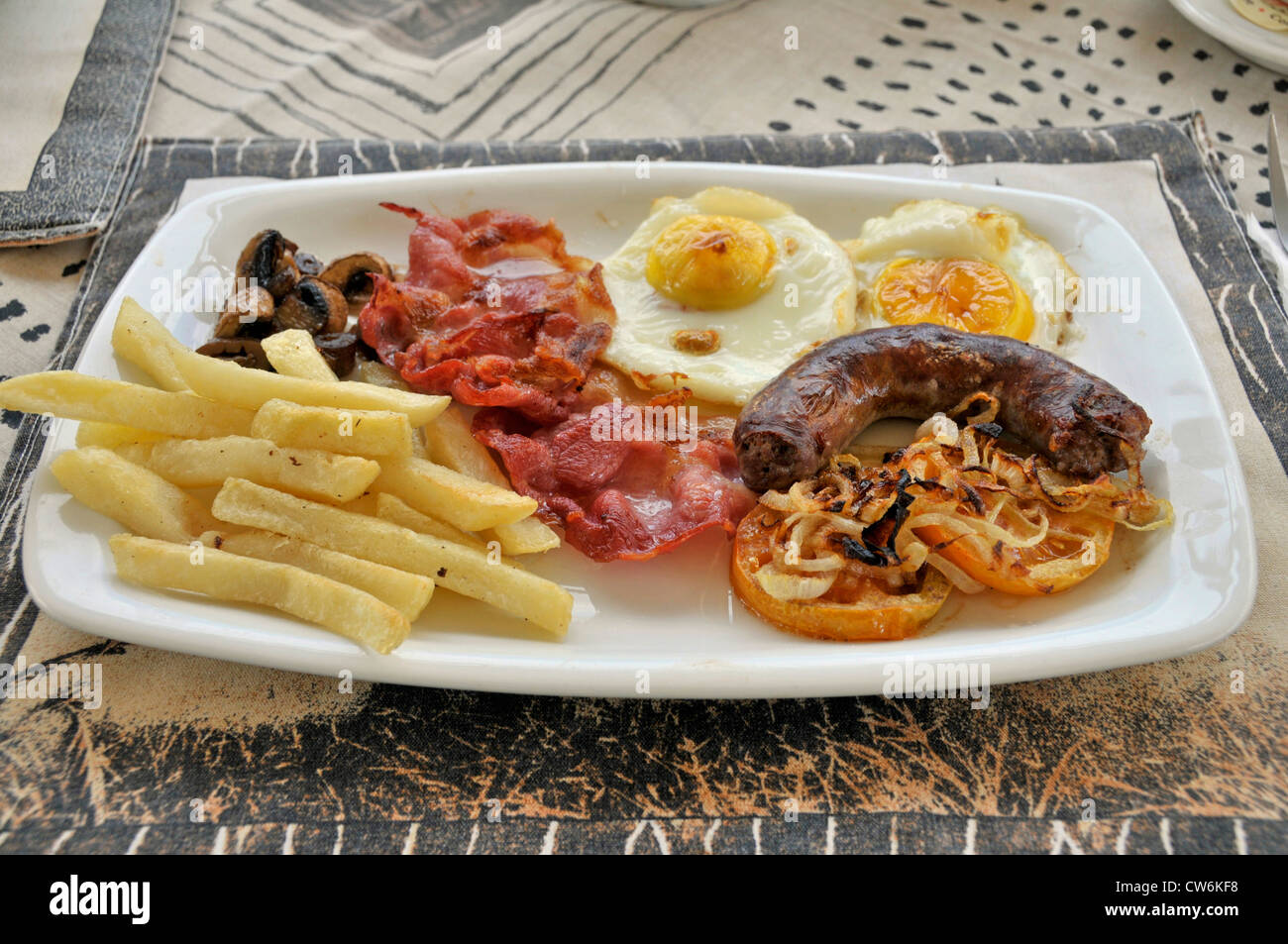 South African breakfirst with french fries, mushrooms, bacon, fried eggs, fish sausage and tomatoes, South Africa Stock Photo