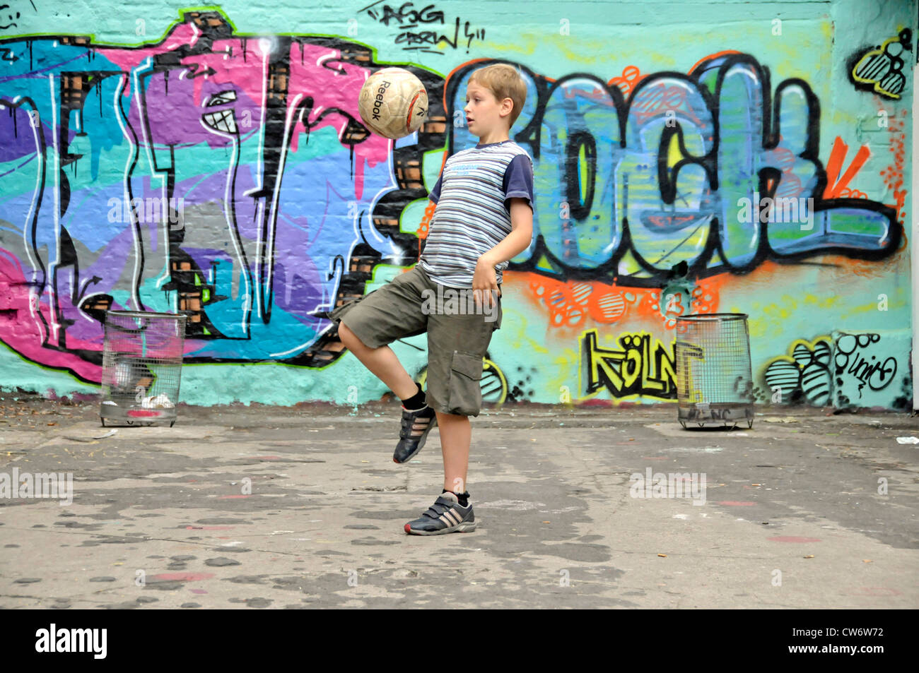 9 years old boy playing football in front of a graffiti wall, Germany, North Rhine-Westphalia, Cologne Stock Photo