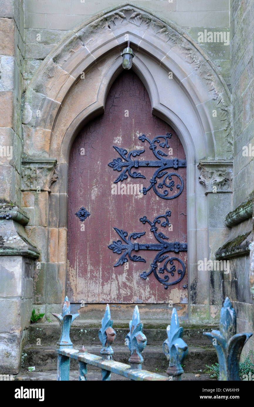 Semi derelict church showing signs of stone work repairs above the heavy iron decorative hinges. Stock Photo
