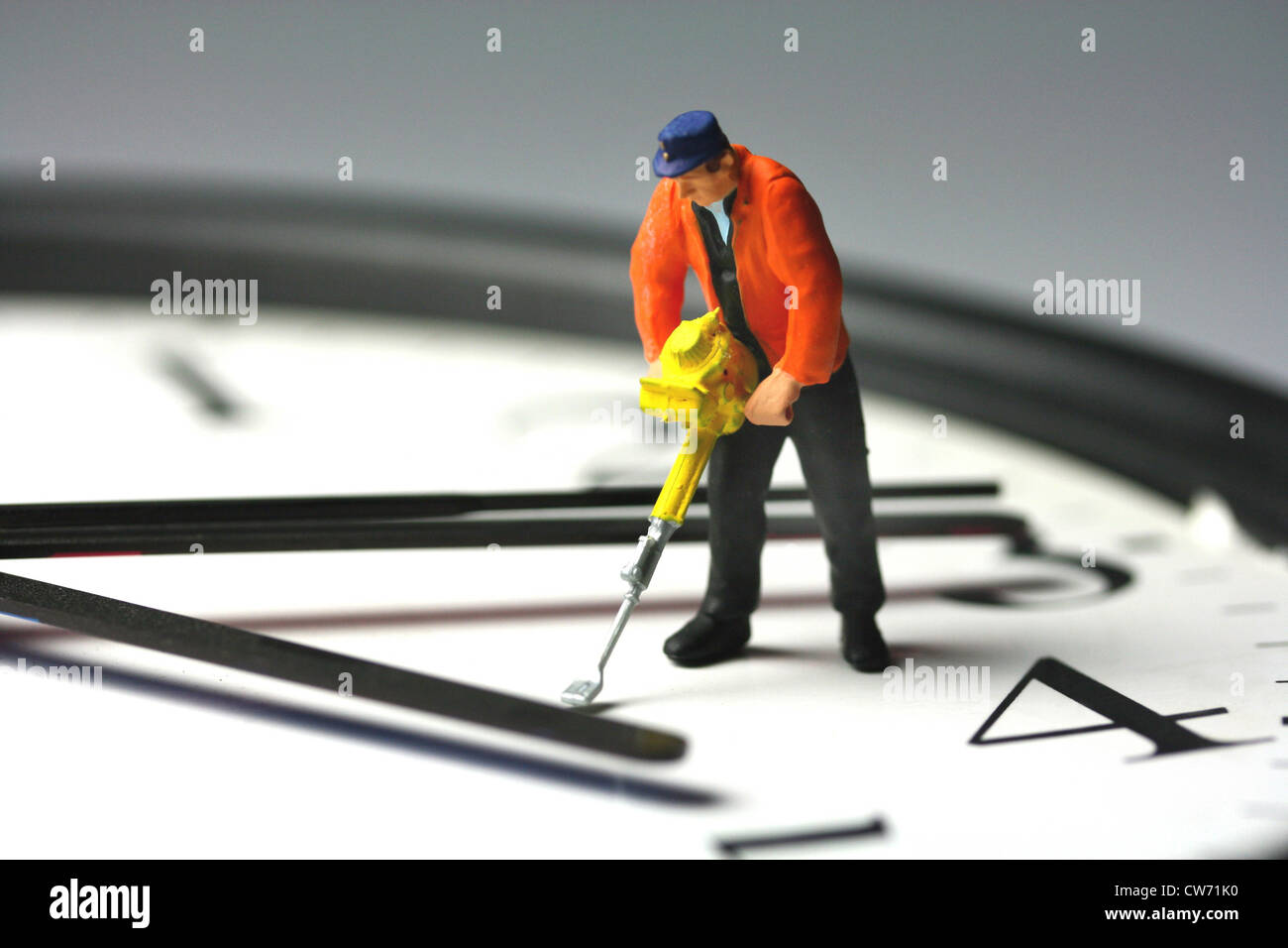 symbol picture 'labour time': model figure of a worker with a pneumatic hammer standing on a clock face Stock Photo