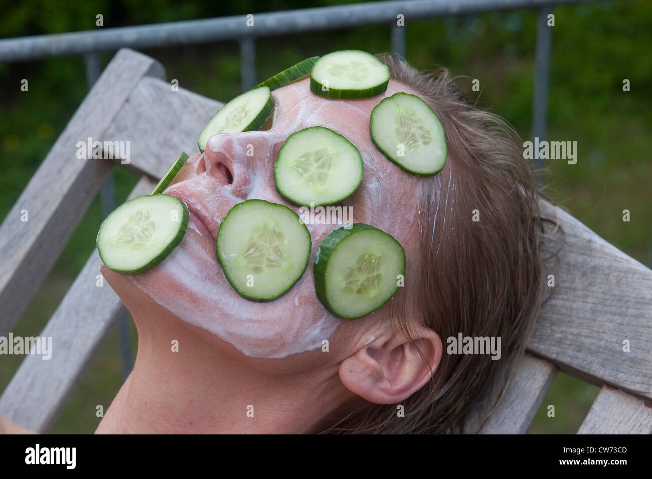 woman lying in a canvas chair with a cucumber mask Stock Photo