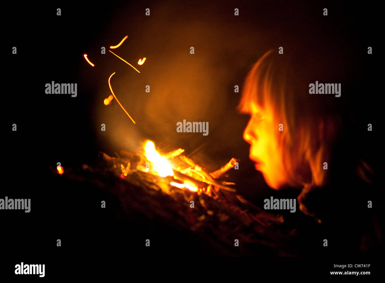 boy at a bonfire, blowing in the heat Stock Photo