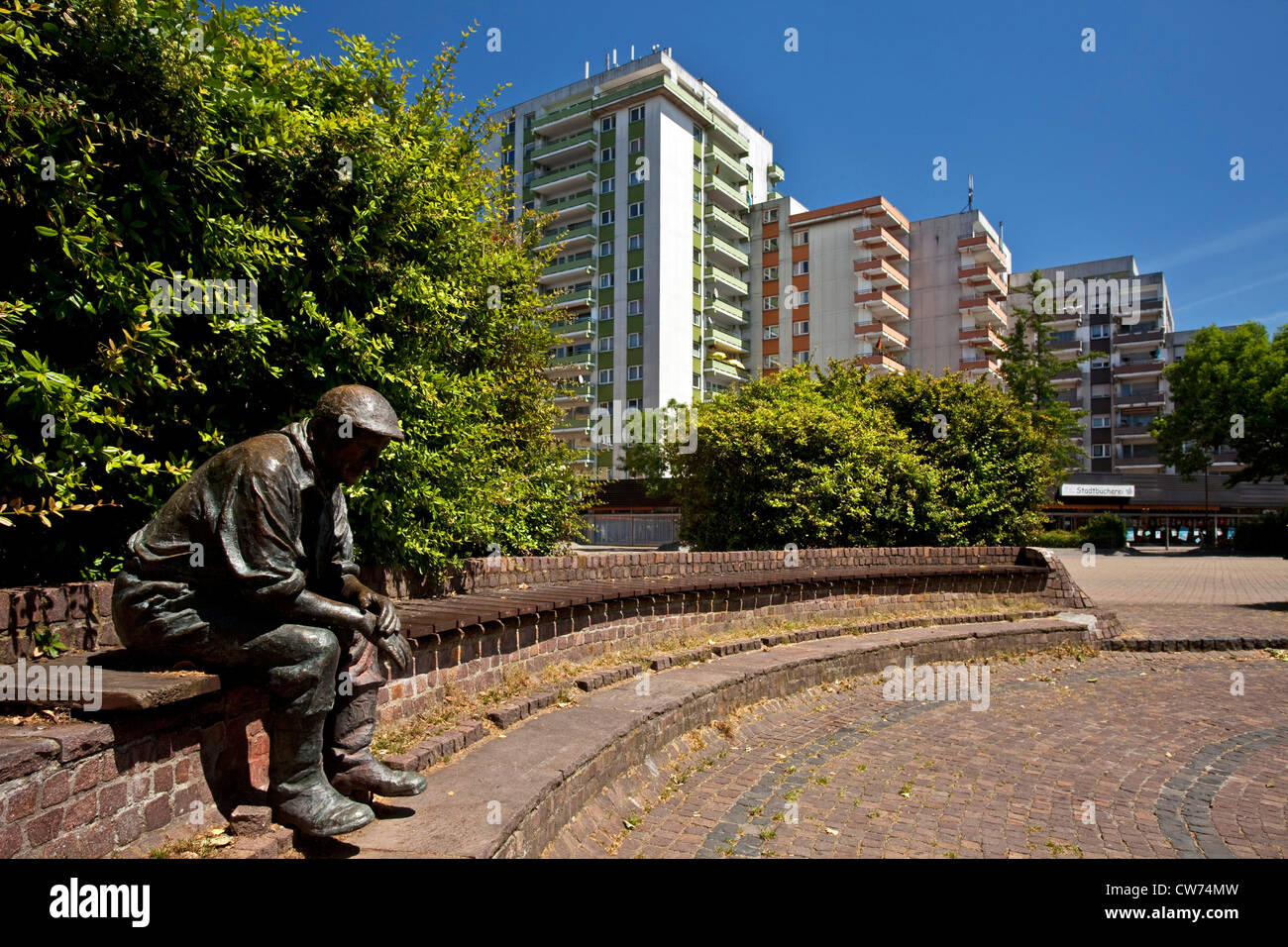 sculpture of a sitting man in front of houses in the city, Germany, North Rhine-Westphalia, Ruhr Area, Kamp-Lintfort Stock Photo