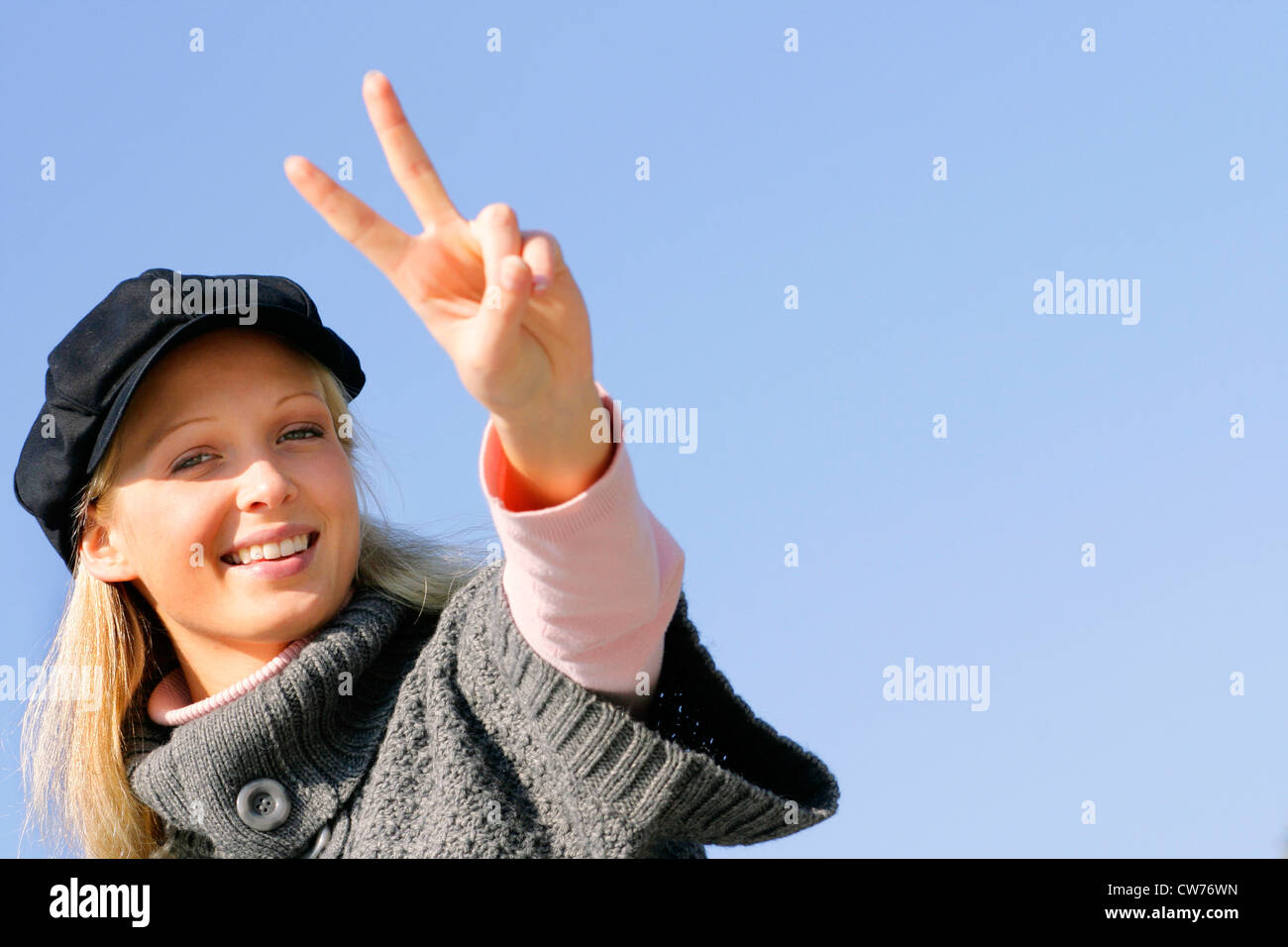 young blond girl with cap, showing the victory sign Stock Photo