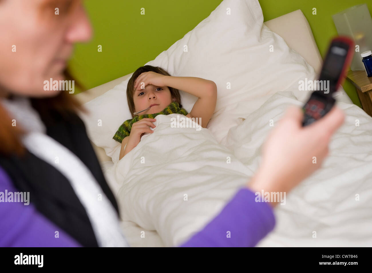 child in bed, mother calls the doctor Stock Photo