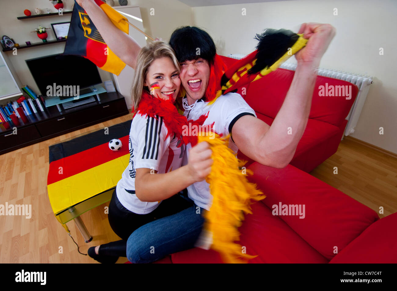 two soccer fans celebrating in living room, Germany Stock Photo