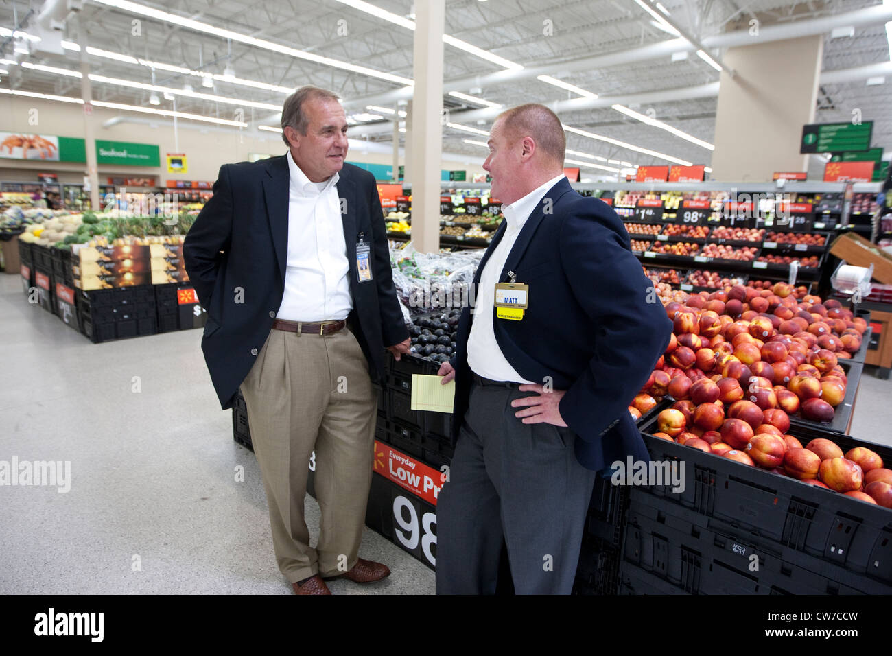 Two white male managers of a WalMart Supercenter talk in produce