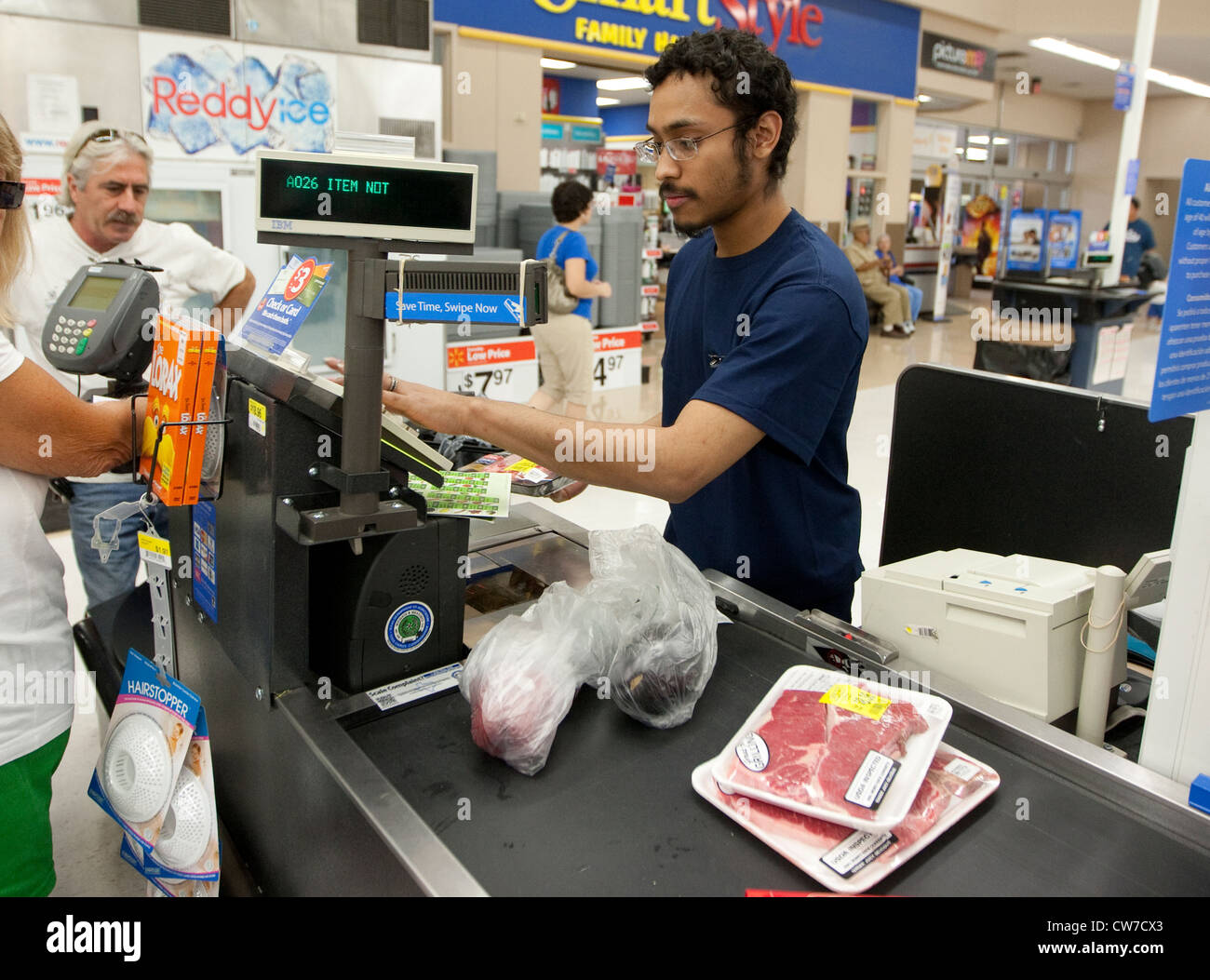 Smiling young Hispanic male cashier rings up products for customer at a Wal-Mart Supercenter in San Marcos, Texas Stock Photo