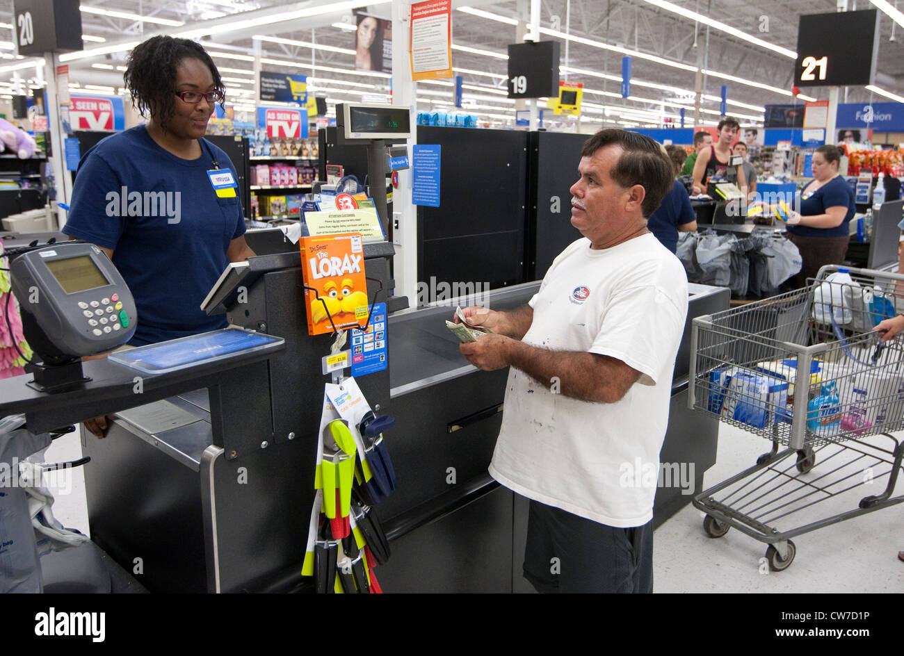 Hispanic male customer counts money to give to African-American female cashier at a Wal-Mart Supercenter in San Marcos, Texas Stock Photo