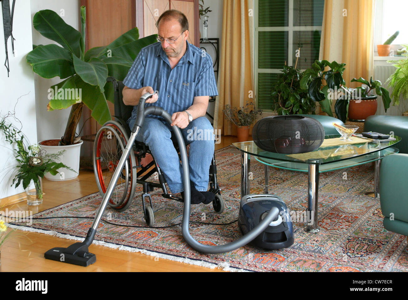 man in a wheelchair using vacuum cleaner Stock Photo Alamy