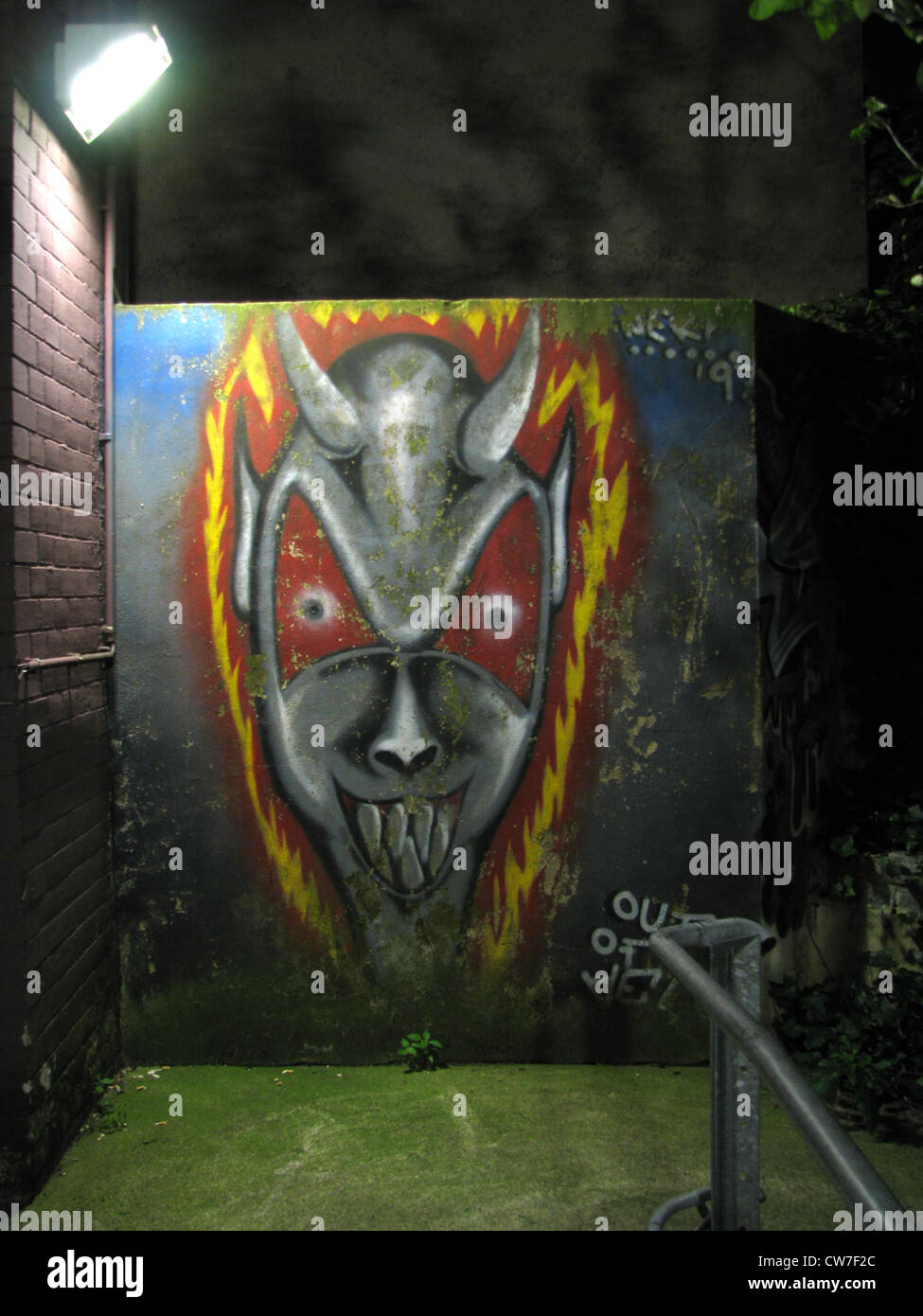 Gloomy grafiti in neon light portrays the devil in a dark backyard, Germany, Hamburg Stock Photo