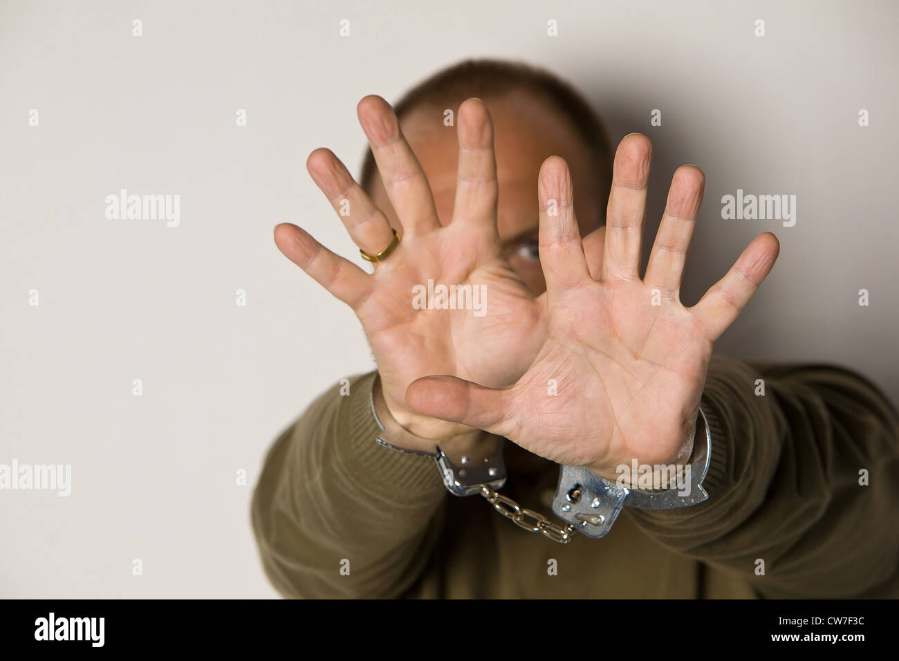closeup of hands in handcuffs obscuring face Stock Photo